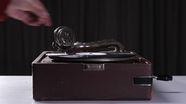 opening the lid of a portable vintage gramophone and starting the vinyl player. retro music concept