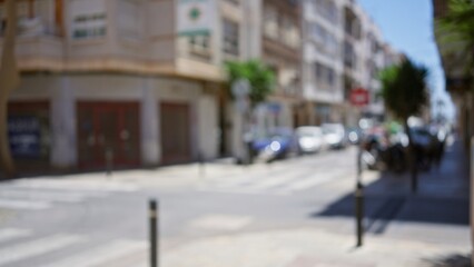 Blurred urban street with defocused buildings and cars under bright daylight