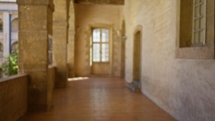 Blurred view of an old university campus corridor with stone walls and arched windows, showcasing a serene outdoor ambiance in soft focus.