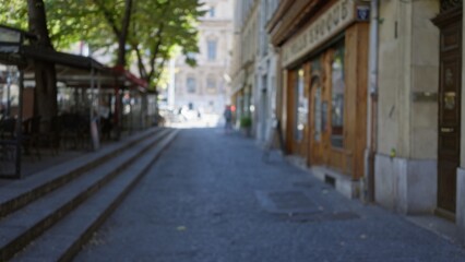Blurred street scene in marseilles with defocused storefronts and tree-lined sidewalk under bokeh effect, capturing europeâ€™s urban charm in a peaceful outdoor setting.