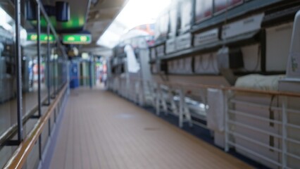 Blurred view of a cruise ship deck outdoors with lifeboats, showcasing defocused bokeh effect and a...