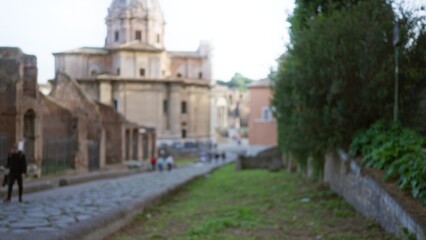 Roman forum scene with blurred people and ancient ruins in the background creating a dreamy bokeh effect showcasing historical architecture in rome.