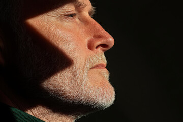 Senior man with white beard showing wrinkles and aging skin in profile view