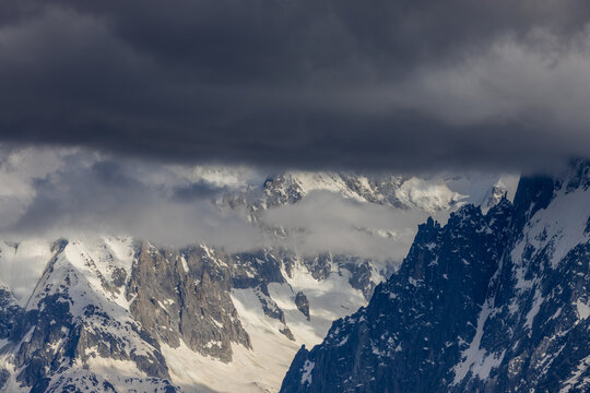 Nasty weather in the Alps. Dark cloudy sky and overcast before the rain and storm. Stormy weather. Snow and rocky summits of the alpine peaks inside the cloud. Aiguilles du Chamonix in autumn 