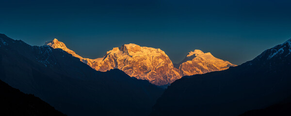 Panoramic view of the snow covered high himalayan mountains after sunset under the colorful blue...