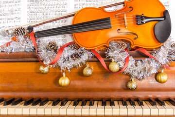 a violin on a piano with christmas bulbs