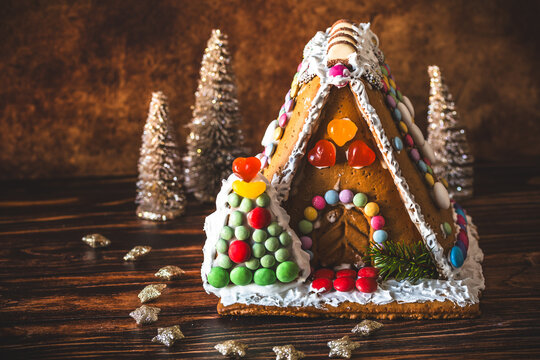 Gingerbread house decorated with colorful candies and christmas decoration on a wooden background