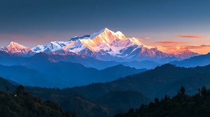 Majestic snow-capped mountain range at sunrise, with layers of hills and valleys in the foreground.