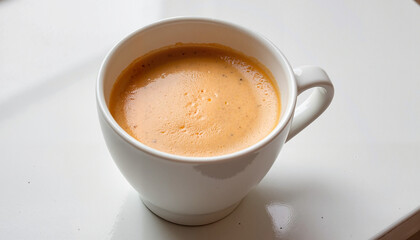 Fototapeta premium Creamy golden turmeric latte in a white cup on a glossy countertop, bright ambiance with copy space