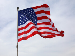 The flag of the United States of America flies against an overcast sky
