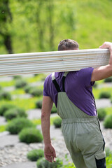 A male worker carries boards for sheathing a gazebo in a lavender field.