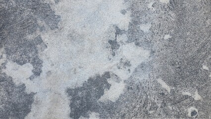 The old grey cement floor has cracks and stains. Black, grey and white grunge wall background.	
