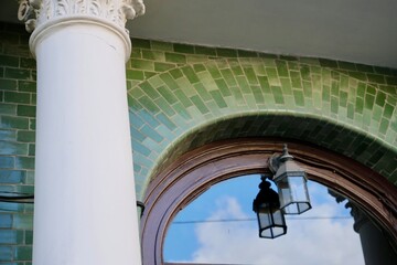 retro style street lamp. semicircular window and hanging green lantern. sky reflected in window, streetscape.