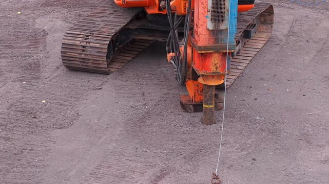 Driving rig piler hammering steel tubular pile deep into ground as part of foundation works