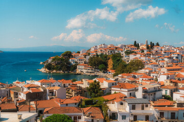 Fototapeta premium Traditional whitewashed houses with orange roofs cover the hillside of skiathos town, creating a charming scene overlooking the aegean sea