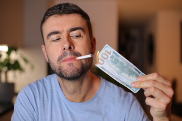 Man burning one hundred dollars to light his cigarette