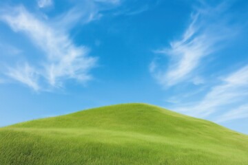 Scenic grassy hill under bright sky. Rich green meadow gently slopes upward. Clear azure sky with wispy white clouds. Ideal rural landscape. Beautiful natural scenery.