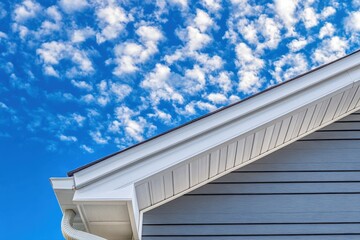 Colonial style white gutter system ventilated soffit and gray vinyl siding in an upscale American neighborhood