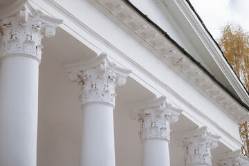 Close-up of white columns of a building with a classical design. The columns are tall and decorated with intricate carvings.