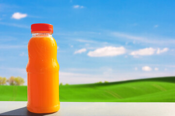 Delicious freshly squeezed orange juice on blurred landscape background