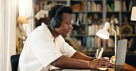 Black man, studying and typing on laptop, home and reading with e learning, development and research in library. Person, computer and student with education, music and online course at apartment