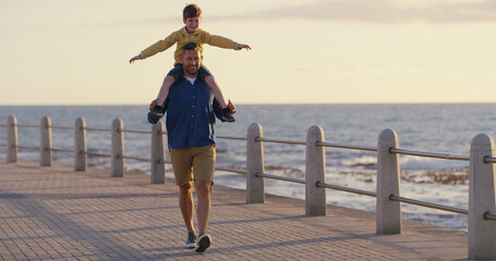 Dad, son and shoulder carry at sea on holiday, adventure and outdoor for bonding with father. Boy, child and papa support with airplane game for freedom, promenade and ocean for love or fun on trip © peopleimages.com