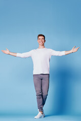 Young handsome man showing welcome gesture. Blue background.