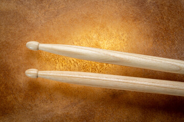 classic 5A wooden drumsticks against backlit drum goat skin