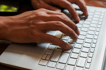 Close Up of man's finger typing on keyboard, Using a laptop in wooden table, business office...