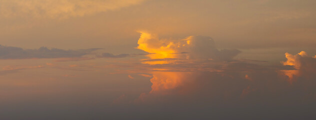 Dramatic sunset sky covered with colorful yellow clouds. Panoramic skyscape