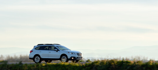 SUV car driving fast on intercity road at sunset. Highway traffic in evening