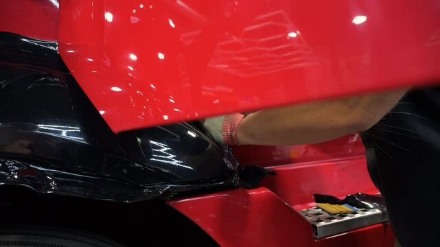 Process of applying a dark PPF film with scraper to a truck with open door. Close up footage of applying a film on a car. 