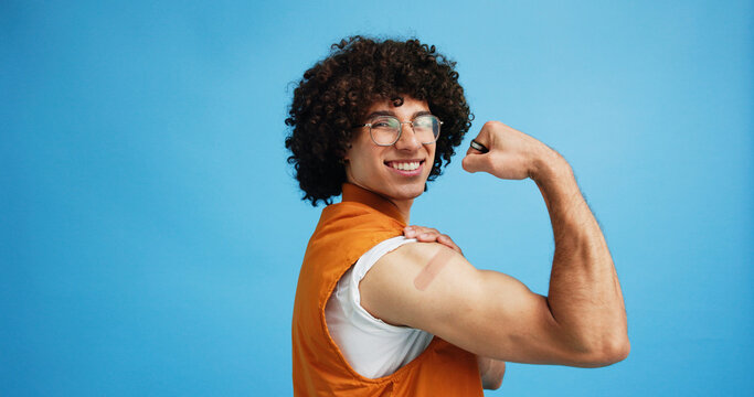 Studio, man and flex with bandage after vaccine, medical treatment and prevention of flu disease. Mockup space, male person or portrait with plaster for healthcare, virus awareness or blue background