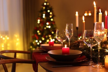 Festive table setting in room decorated for Christmas, closeup. Bokeh effect