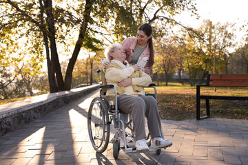 Caregiver with elderly woman in wheelchair at park