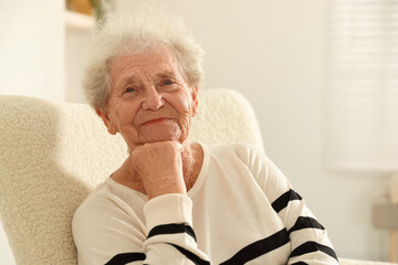 Beautiful senior woman sitting on armchair at home