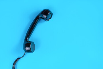 Old retro telephone handset on a classic blue background in a studio. Telecommunication and minimalism concept with copy space for text or design