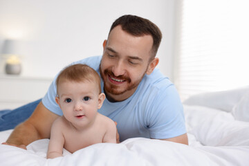 Father with his cute baby on bed at home