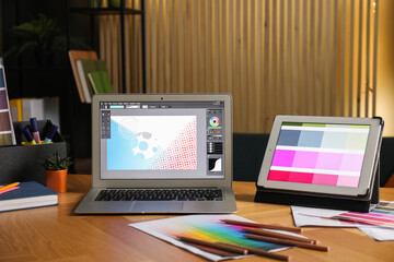 Designer's workplace with laptop, tablet, stationery and palettes on wooden table indoors