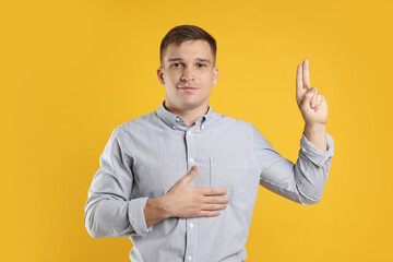 Man showing oath gesture on orange background. Making promise