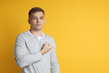 Man making promise on orange background, space for text. Oath gesture