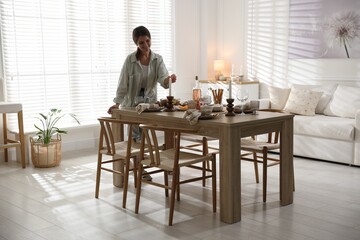 Woman setting table for dinner at home