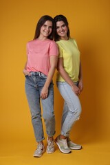 Portrait of happy twin sisters on orange background