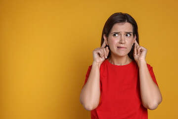 Woman showing hand to ear gesture on orange background, space for text