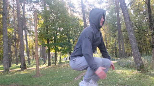 High jump exercise by an athlete in nature. Dynamic movement during a warm-up session. Focus on legs, shoes. Outdoor activity