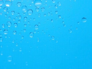 Water drops glistening on a vibrant blue background, creating a fresh and calming atmosphere, tranquility, water