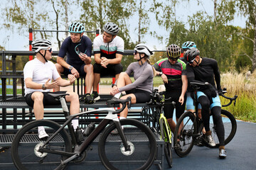 Group of athletic people with helmets and bicycles spending time together outdoors