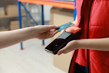 Obraz premium Woman paying for service with credit card via terminal indoors, closeup