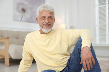 Smiling senior man sitting on floor at home