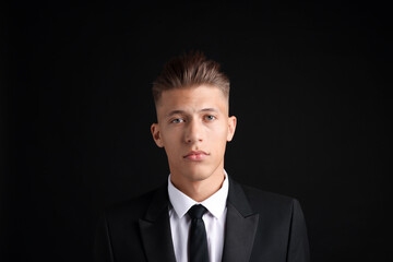 Confident young man with stylish haircut on black background